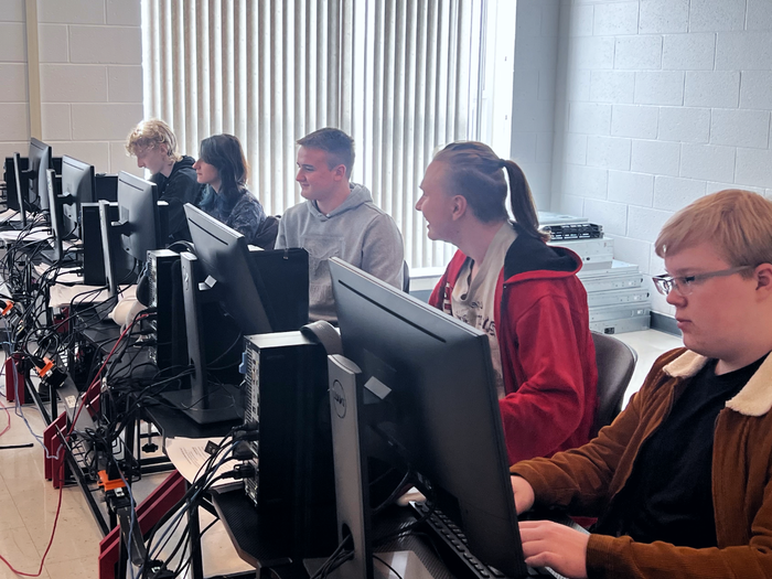 Five students sitting at computers in a computer lab